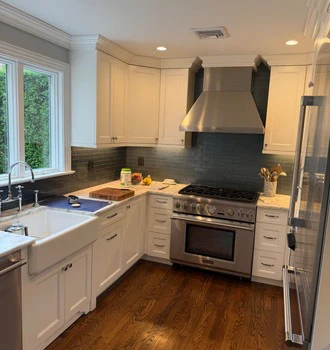 White kitchen with painted cabinetry, hood and tile backsplash