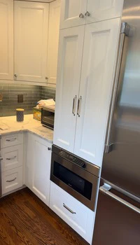 Painted white cabinetry and paneled refrigerator surround finished by United Painting